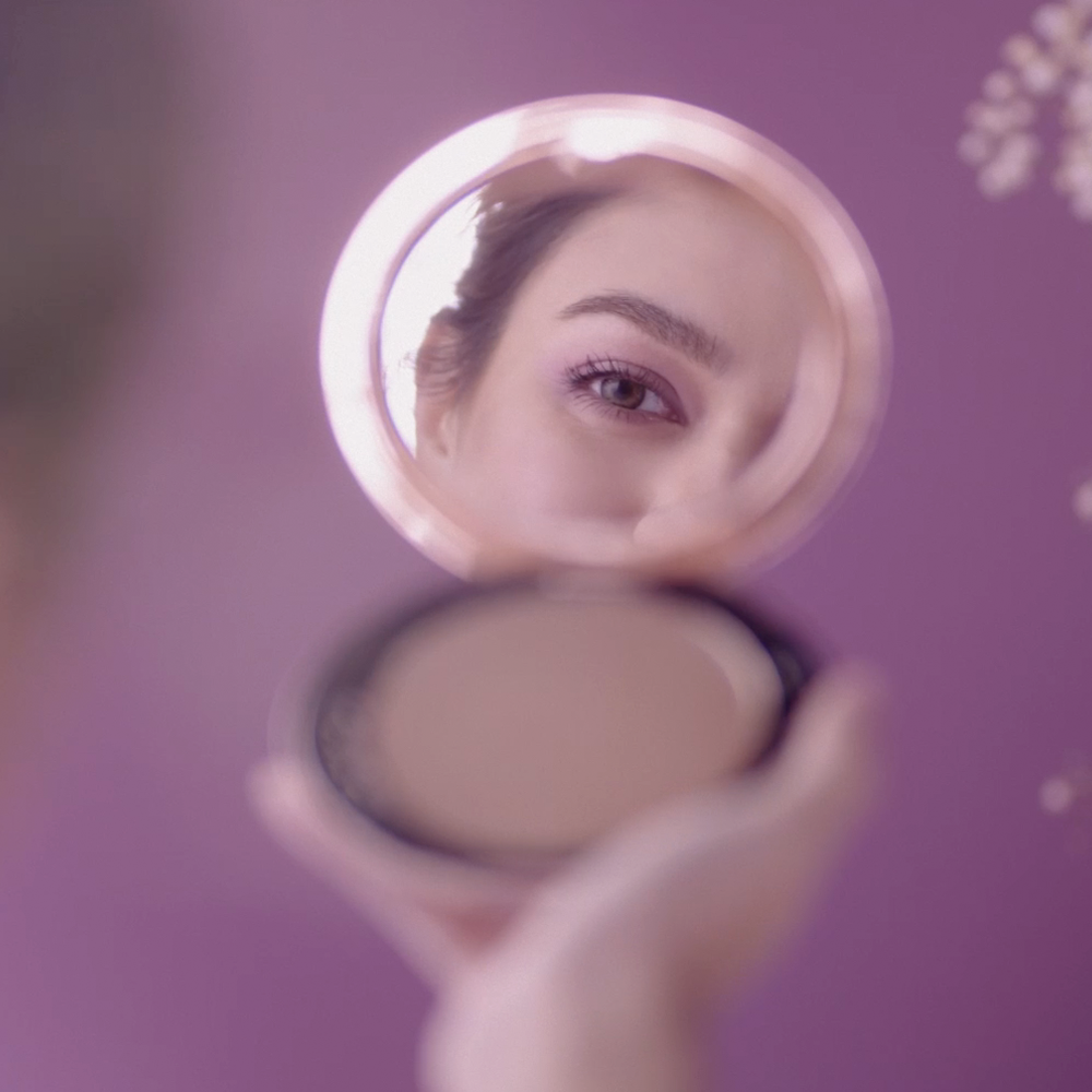 Woman looking at eyes through a reflection in makeup mirror showing