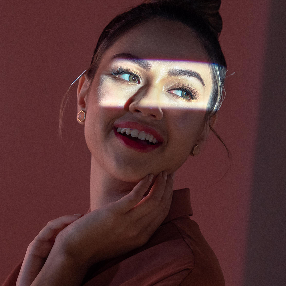 Woman smiling with light shining on her face highlighting her colorful eyes