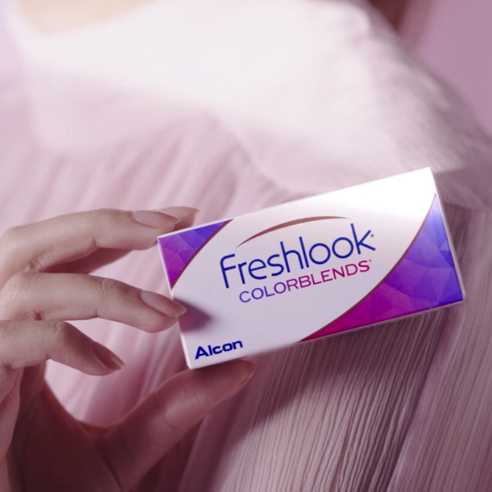 Woman's hand holding a box of Freshlook Colorblends color contact lenses